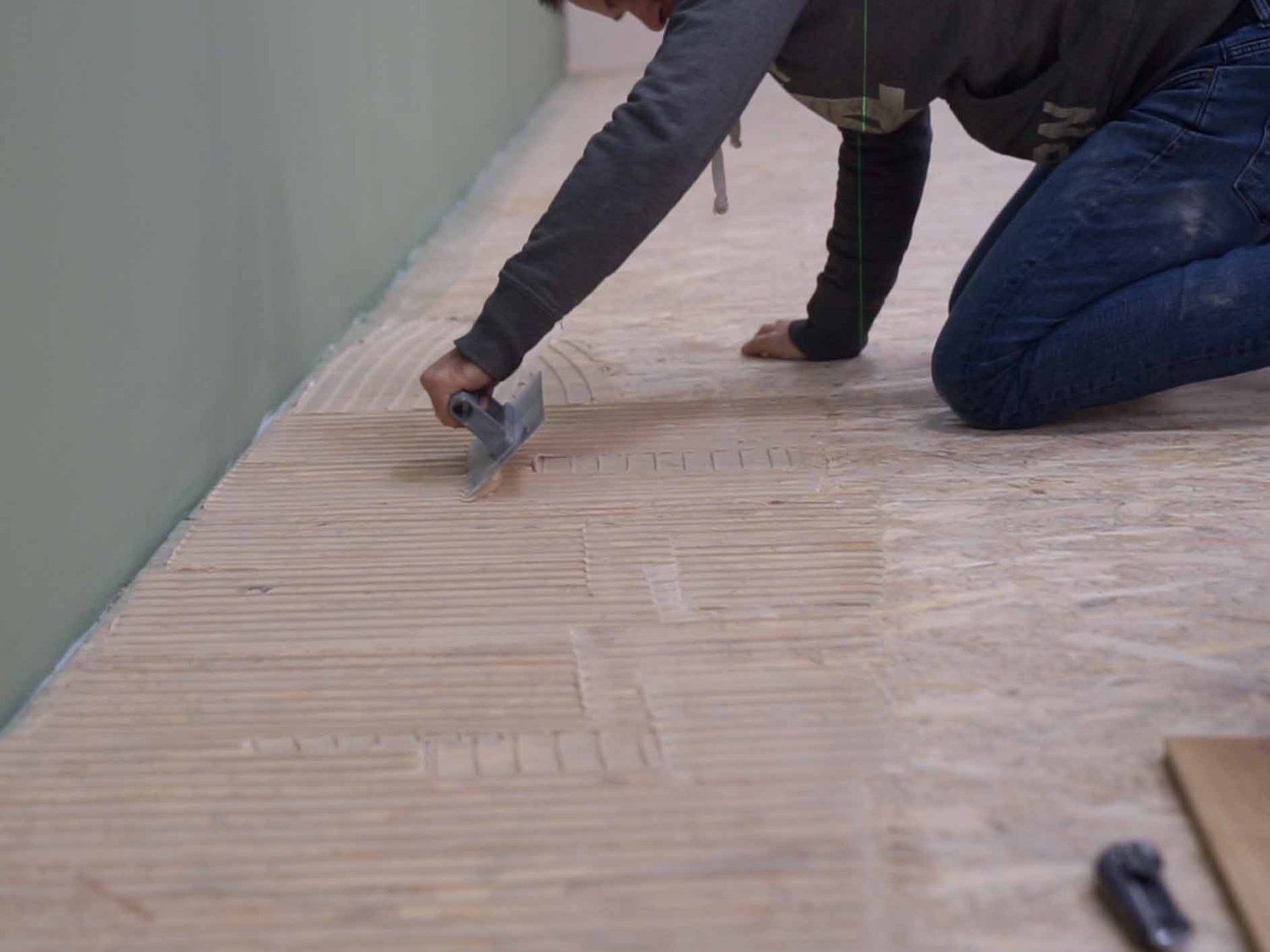 Applying adhesive with a notched trowel onto the subfloor
